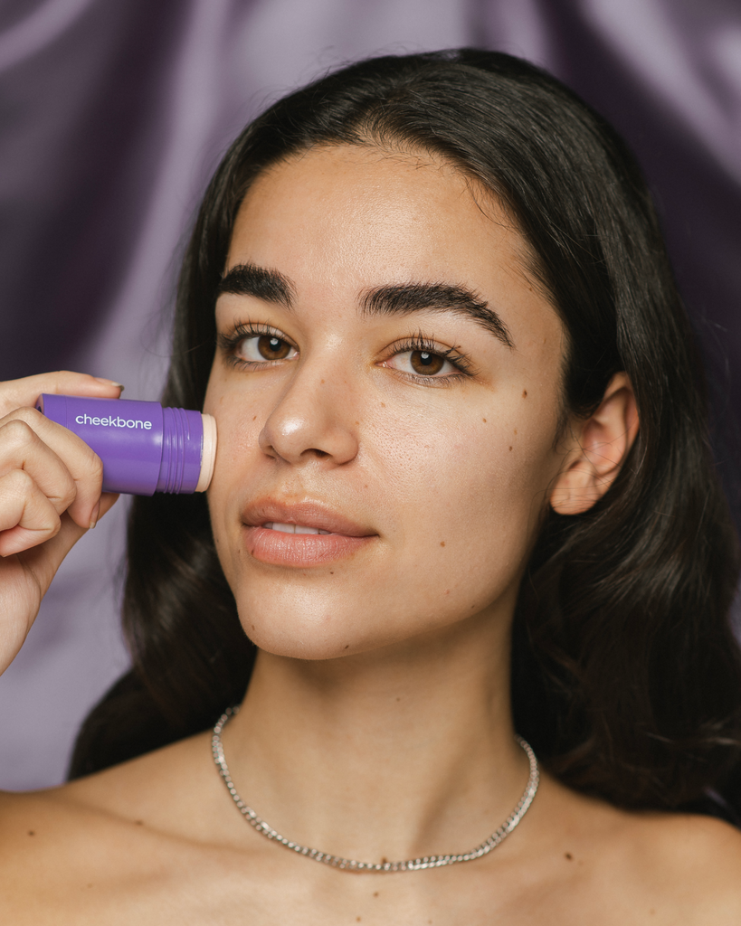 Model applying Starlight Illuminating Primer Stick to their face.